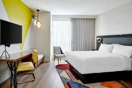a bedroom with a bed and a desk and a tv at Hotel Celare, Cincinnati Midtown, a Tribute Portfolio Hotel in Cincinnati