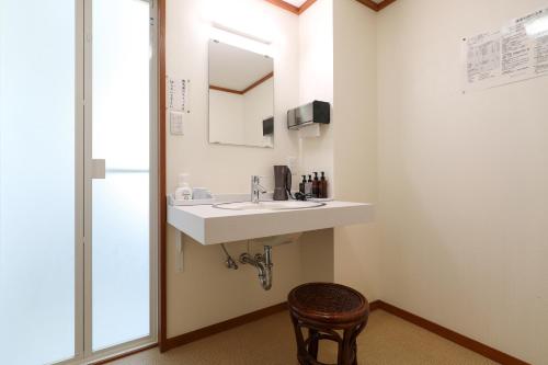 a bathroom with a sink and a mirror and a stool at 赤湯温泉 丹泉ホテル in Nanyo