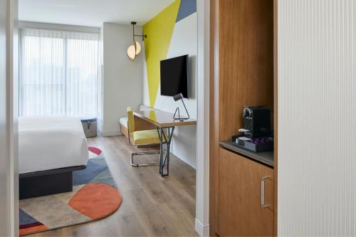 a hotel room with a bed and a desk with a television at Hotel Celare, Cincinnati Midtown, a Tribute Portfolio Hotel in Cincinnati