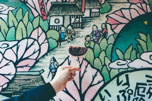 a person holding a piece of food in front of a mural at Kakegawa Grand Hotel in Kakegawa
