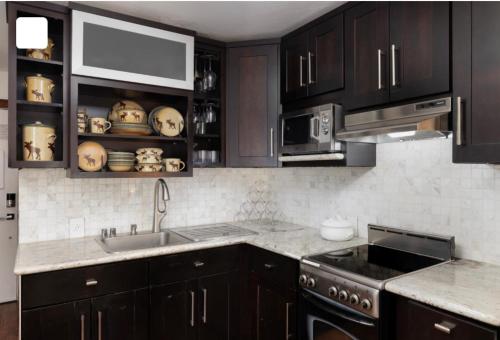 a kitchen with black cabinets and a sink and a stove at Perfect Inside Downtown Aspen Location! Romantic 1300 ft, 4 Blocks or 396 m, to AJAX or Aspen Mountain in Aspen