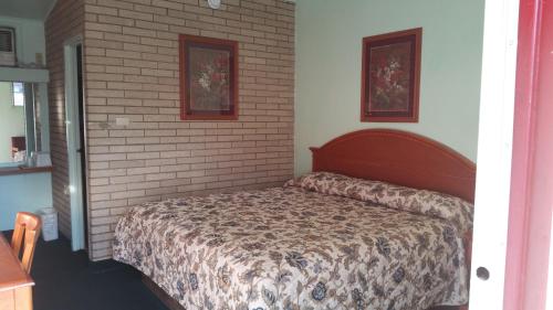 a bedroom with a bed with a brick wall at Budget Inn Heber Springs in Heber Springs