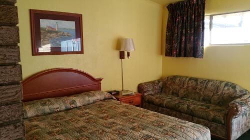 Budget Inn Heber Springs في Heber Springs: غرفه فندقيه بسرير واريكه