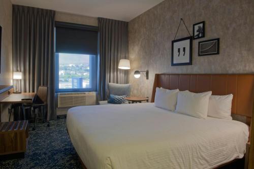 a hotel room with a bed and a desk and a window at Four Points by Sheraton Distrito Uno Chihuahua in Chihuahua