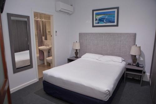 a bedroom with a large white bed and a bathroom at Savoy Double Bay Hotel in Sydney