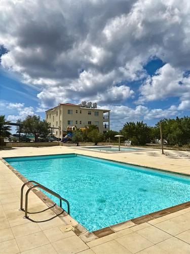 a large blue swimming pool with a building in the background at Spacious sea view apartment in Chlorakas