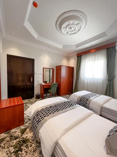 a hotel room with two beds and a desk at رواح للشقق المخدومة السداد in Taif