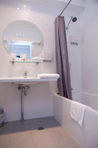 a bathroom with a sink and a mirror and a tub at Savoy Double Bay Hotel in Sydney