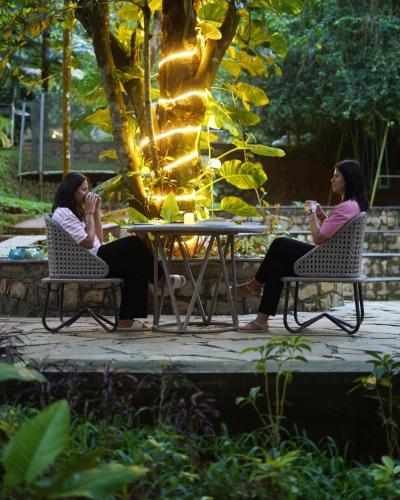 two women sitting at a table in a garden at Raindrops Resorts Wayanad in Sultan Bathery