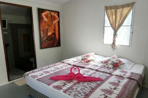 two pink slippers sitting on a bed in a bedroom at Sleep Whale Lanta in Ko Lanta