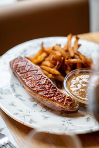 a plate of food with a piece of fish and french fries at Grand Hôtel d'Orléans in Toulouse
