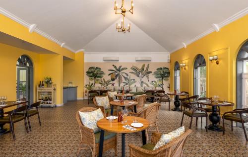 a restaurant with tables and chairs and yellow walls at The Source At Sula in Nashik