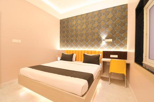 a bedroom with a bed and a desk with a yellow chair at Hotel Sai Swastik in Puri
