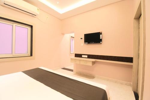 a bedroom with a bed and a tv on the wall at Hotel Sai Swastik in Puri