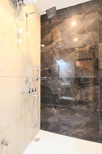 a bathroom with a shower with a black marble wall at Hotel Sai Swastik in Puri