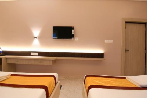 a room with two beds and a tv on the wall at Hotel Sai Swastik in Puri