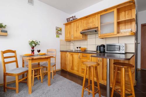 una cocina con armarios de madera, mesa y sillas en Bright Studio with Balcony in Murzasichle by Noclegi Renters, en Murzasichle