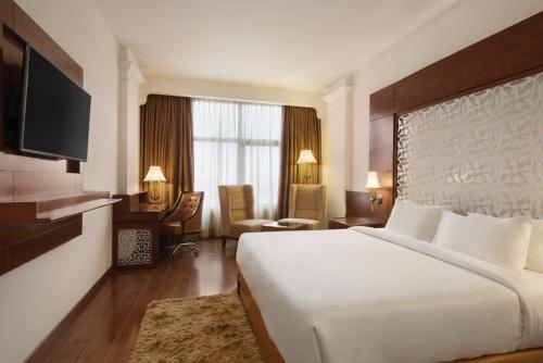 a hotel room with a large bed and a desk at Ramada Plaza By Wyndham, Chandigarh Zirakpur in Chandīgarh