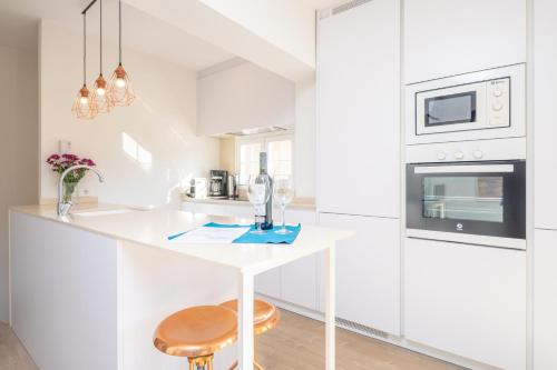 a white kitchen with a counter and a stool at Vacances Felanitx in Felanitx