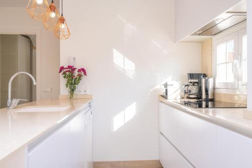 a white kitchen with white counters and a vase of flowers at Vacances Felanitx in Felanitx