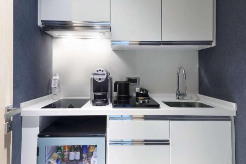 a small kitchen with white cabinets and a sink at Wyndham Grand Istanbul Levent Hotel & Conference Center in Istanbul