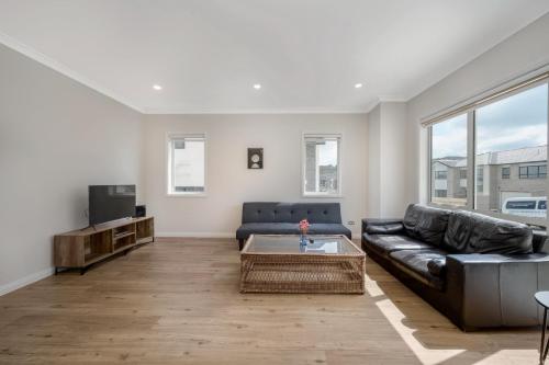 a living room with a couch and a tv at Designer Brand New Large House Flat bush in Manukau City