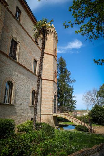 a building with a palm tree next to a bridge at Castello Montegiove in Fano