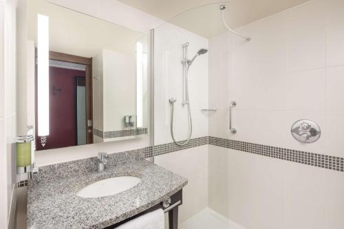 a white bathroom with a sink and a shower at Hampton by Hilton London Gatwick Airport in Horley