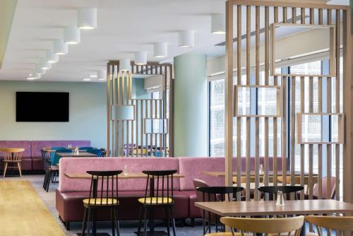a restaurant with a pink couch and tables and chairs at Hampton by Hilton London Gatwick Airport in Horley