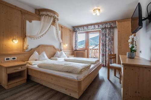 a bedroom with a large bed and a window at Pensione Camoscio in La Villa