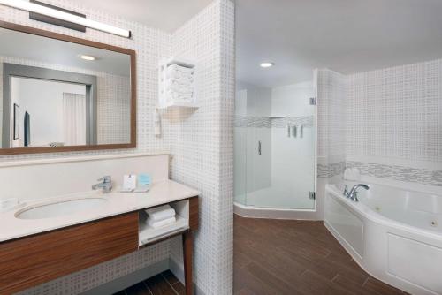 a bathroom with a tub and a sink and a mirror at Hampton Inn and Suites Clearwater Beach in Clearwater Beach