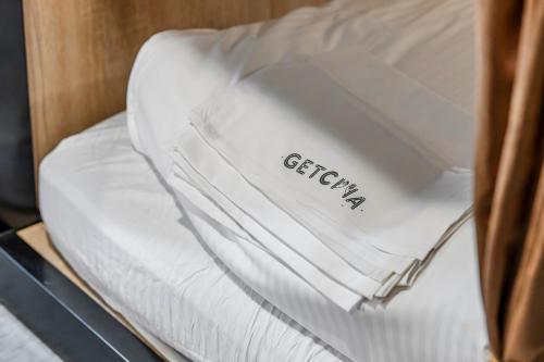 a pile of white sheets on top of a bed at Getcha Hostel in Taichung