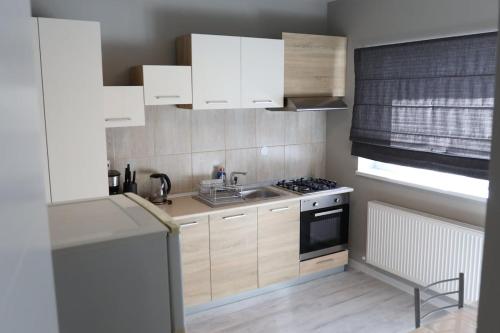 a kitchen with white cabinets and a sink and a stove at NC Rezidence Apartment 5 in Craiova