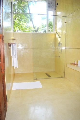 a bathroom with a shower with a glass door at Madiha Venus in Matara