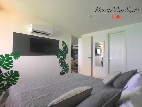 a bedroom with a bed with a tv on the wall at Beira Mar Suite in Fortaleza