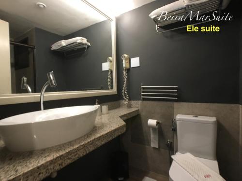 a bathroom with a sink and a toilet and a mirror at Beira Mar Suite in Fortaleza