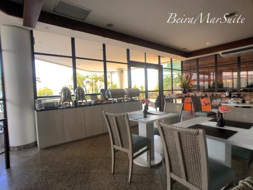 a restaurant with tables and chairs and a counter at Beira Mar Suite in Fortaleza