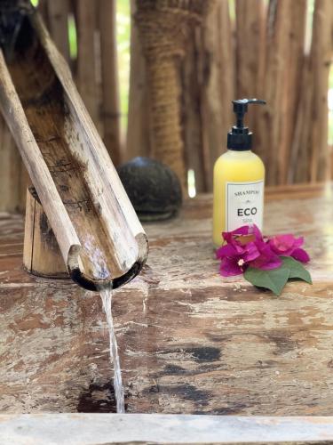 a bottle of soap and flowers on a table at The Nest Tropical Oasis Resort in Paje