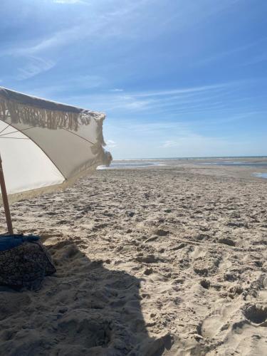 - une plage avec un parasol sur le sable dans l'établissement Joie de vivre le touquet, à Le Touquet-Paris-Plage