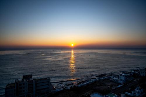 釜山Mer de laube Hotel的海滩和建筑的日落