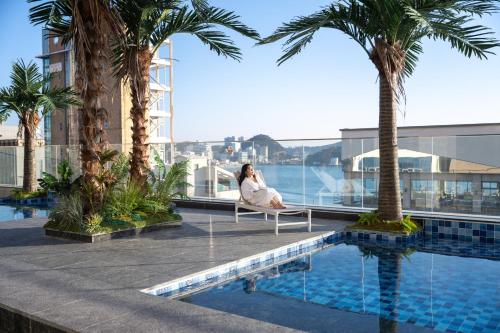 a woman sitting on a chair next to a swimming pool at Mer de laube Hotel in Busan