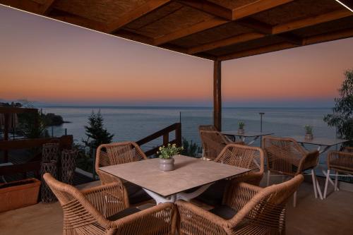 a table and chairs on a patio with a view of the ocean at Pelagos Blue Zante in Vasilikos
