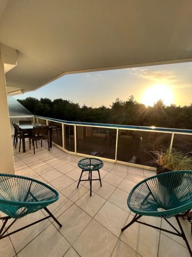 d'un balcon avec 3 chaises et une table sur la terrasse. dans l'établissement Joie de vivre le touquet, à Le Touquet-Paris-Plage