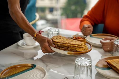 una persona che tiene un piatto di cibo su un tavolo di SKI Hotels and Resorts Rishikesh a Rishikesh