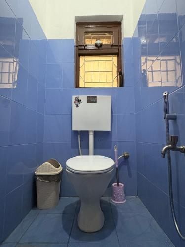 bagno blu con servizi igienici e finestra di DRAKON NEST HOMESTAY a Kathmandu