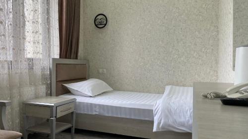 a bedroom with a bed and a clock on the wall at Diyor Hotel in Margilan