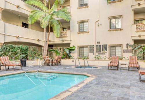 an outdoor pool with chairs and a palm tree at LALA House -1Br with Free Parking, Pool, Laundry in Los Angeles
