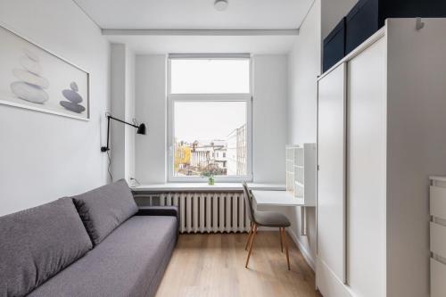 a living room with a couch and a desk and a window at Hook Studios Vilnius Old Town Economy in Vilnius