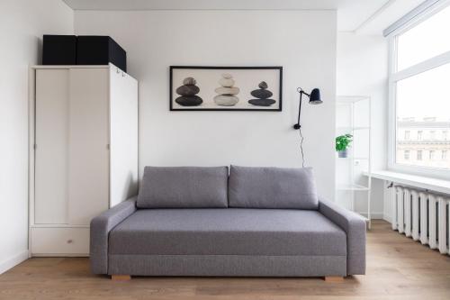 a gray couch in a white room with a window at Hook Studios Vilnius Old Town Economy in Vilnius
