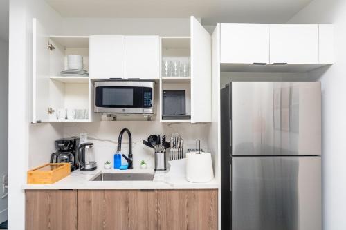 a kitchen with white cabinets and a stainless steel refrigerator at Urban Oasis in Miami Close to Bayside and Brickell with Free Parking in Miami